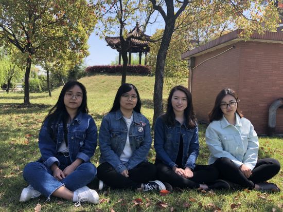 图为：李悦、罗丹桐、周沁心、陈优琪穿着统一的牛仔外套坐在树荫下。 校方提供